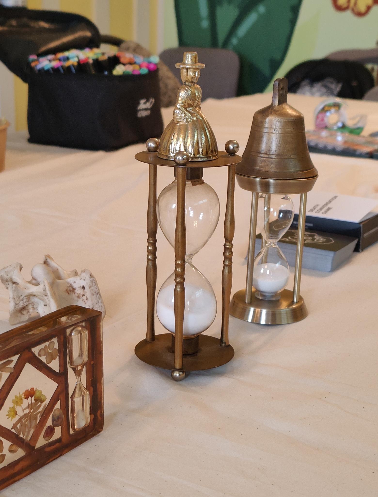 A table set for an Hourglass gathering with hourglasses, bells, and creative materials